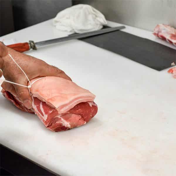 Butcher tying meat on chopping board sq